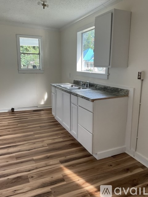 A kitchen with wooden floors and white cabinets.