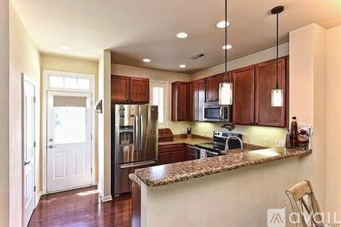 A kitchen with brown cabinets and a granite counter top.
