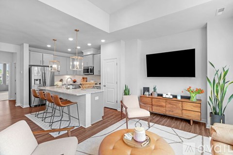 A modern kitchen with a dining table and chairs, a sofa, and a TV on the wall.