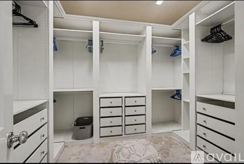 A spacious walk-in closet with white shelving and drawers.