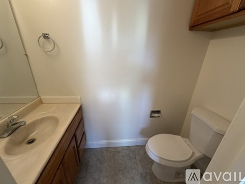 A bathroom with a toilet, sink, and mirror.