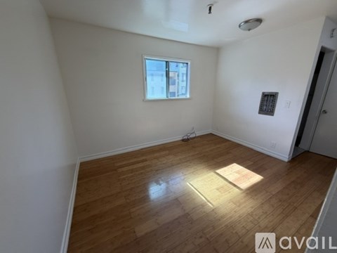 A room with wooden flooring and a window.