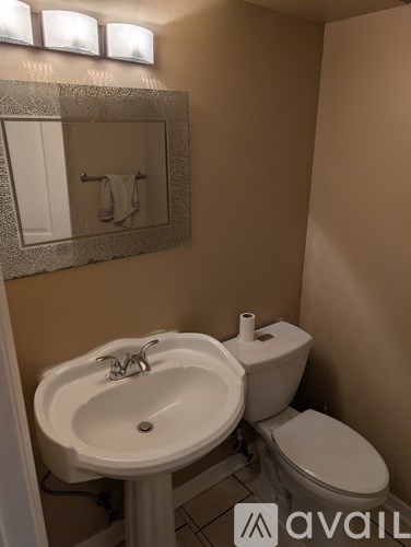 A bathroom with a toilet, sink and mirror.