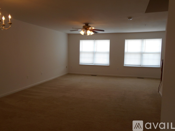 A room with a ceiling fan and two windows.