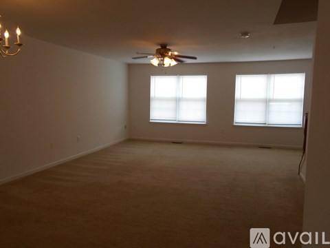 A room with a ceiling fan and two windows.
