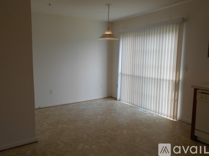 A room with a hanging light fixture and a window with blinds.