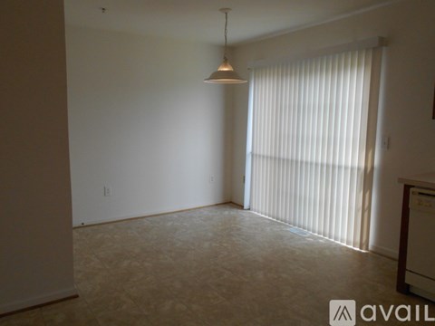A room with a hanging light fixture and a window with blinds.
