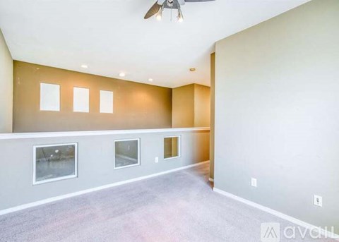 A spacious room with a ceiling fan and three windows.