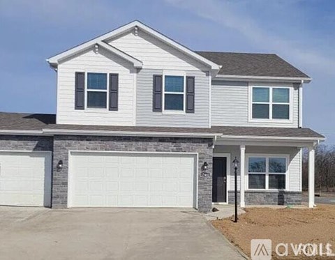 A two-story house with a garage and a brick base.