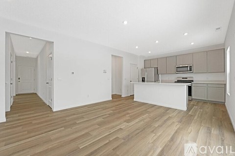 A spacious kitchen with wooden flooring and white walls.