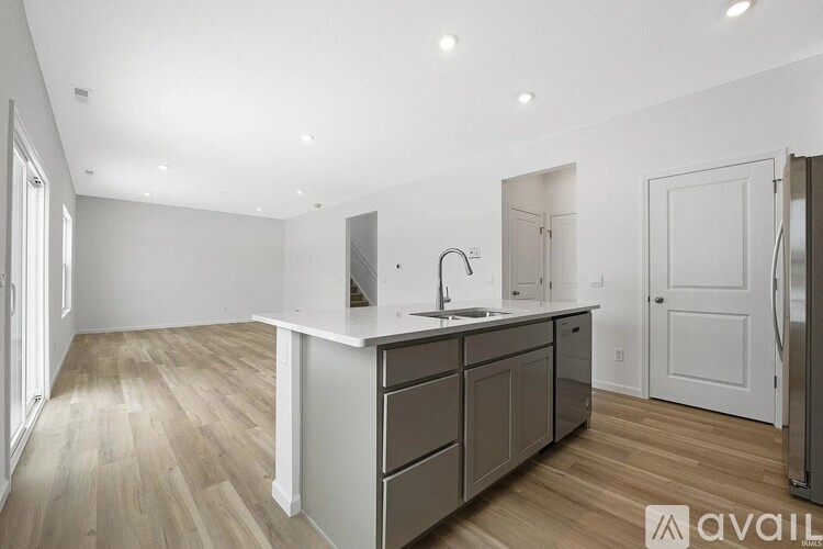 A kitchen with a sink, cabinets, and a refrigerator.