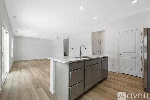 A kitchen with a sink, cabinets, and a refrigerator.