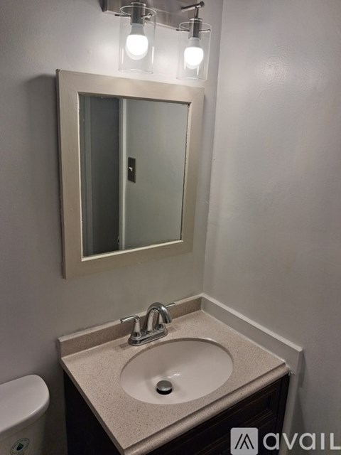 A bathroom with a sink, mirror and light.