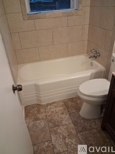 A bathroom with a tub, toilet and tiled floor.