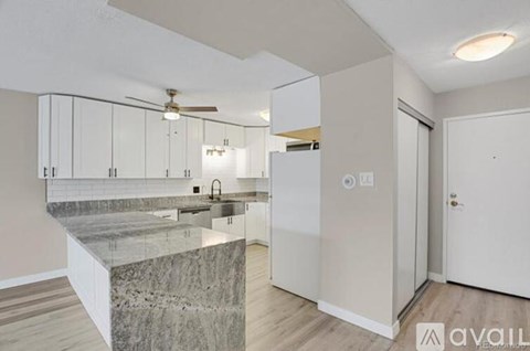 A modern kitchen with a marble countertop and white cabinets.