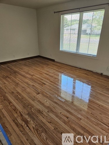 A room with wooden flooring and a window with blinds.