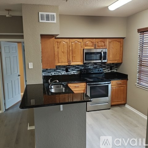 A kitchen with wooden cabinets and black countertops.