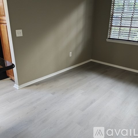 A room with a light grey wall and a window with blinds.