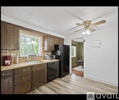 A kitchen with wooden cabinets and a black refrigerator.