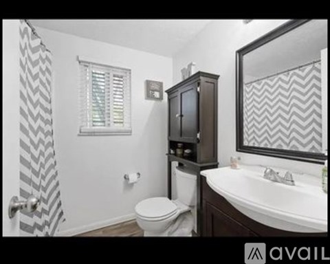 A bathroom with a toilet, sink, and a cabinet.