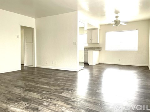 A spacious room with wood flooring and a ceiling fan.