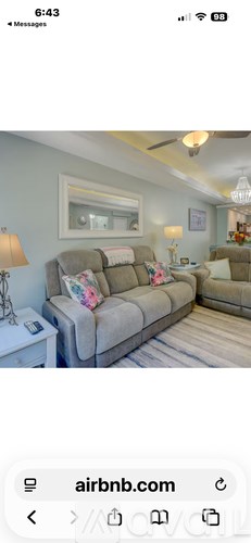 A living room with a grey couch and a white side table.