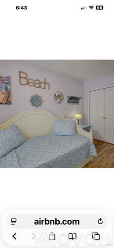 A bedroom with a bed and a wall decoration that says "Beach".