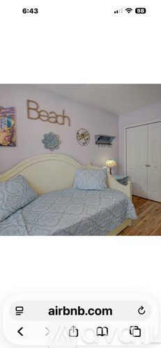 A bedroom with a bed and a wall decoration that says "Beach".