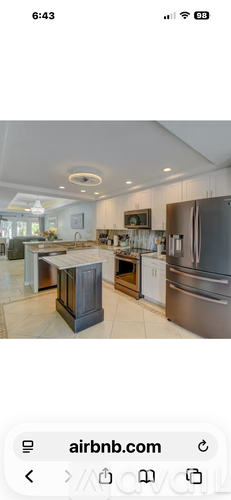 A kitchen with a refrigerator, sink, and cabinets.