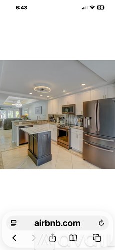 A kitchen with a refrigerator, sink, and cabinets.