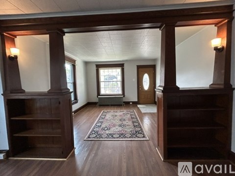 A room with wooden floors and a rug in the middle.
