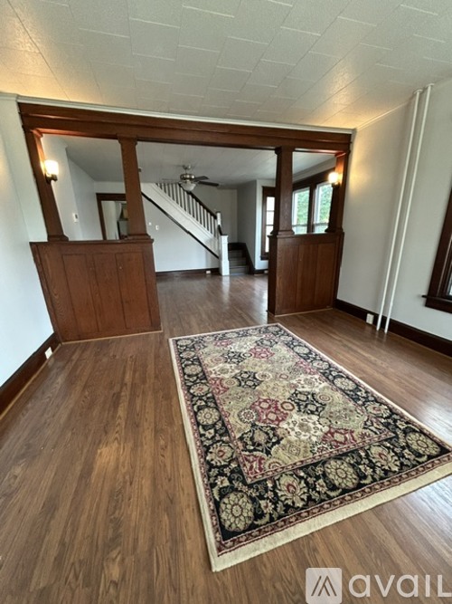 A large rug with a pattern of red, black and white colors is on a wooden floor.