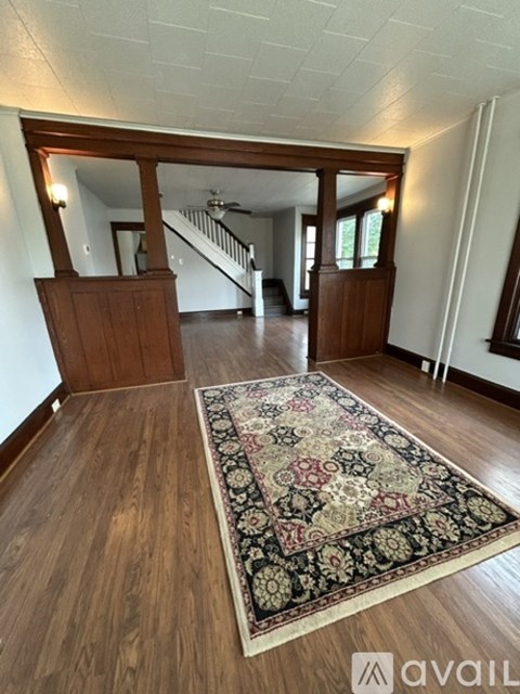 A large rug with a pattern of red, black and white colors is on a wooden floor.