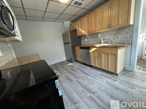 A kitchen with a black stove top oven and wooden cabinets.