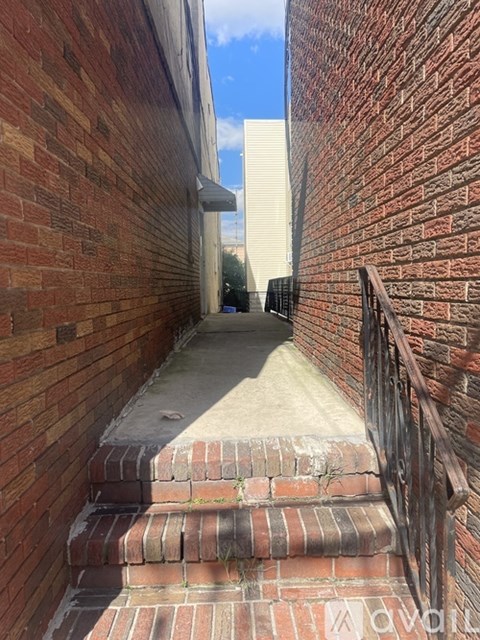 A narrow alley with brick walls and steps leading up.