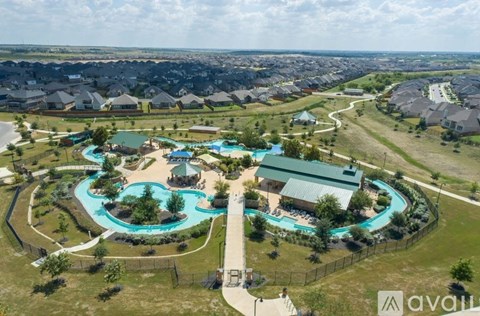 A large aerial view of a resort with a swimming pool and a building with a green roof.
