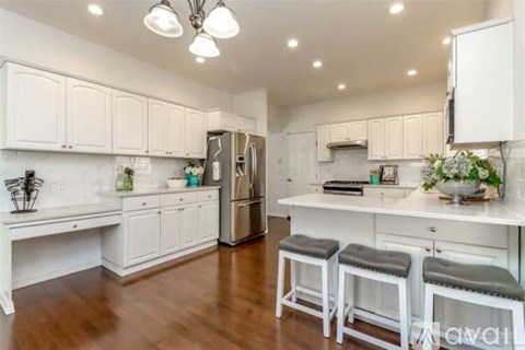 A kitchen with white cabinets and a refrigerator.