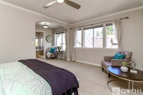 A bedroom with a bed, a couch, and a ceiling fan.