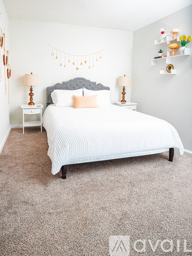 A bedroom with a large bed and two lamps.