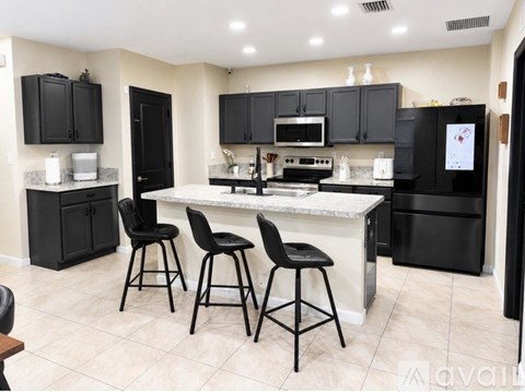 A kitchen with black cabinets and a white island.