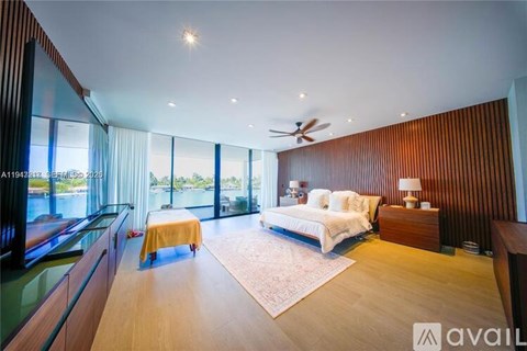 A bedroom with a bed, a chair, and a table with a lamp on it.