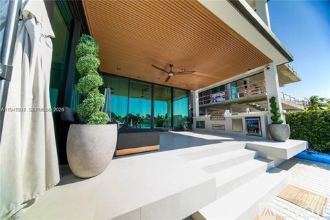 A modern outdoor kitchen area with a wooden ceiling and a pool in the background.