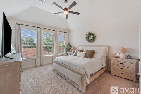 A bedroom with a large bed, a flat-screen TV, and a ceiling fan.