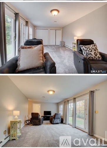 A living room with a black leather couch and a grey carpet.