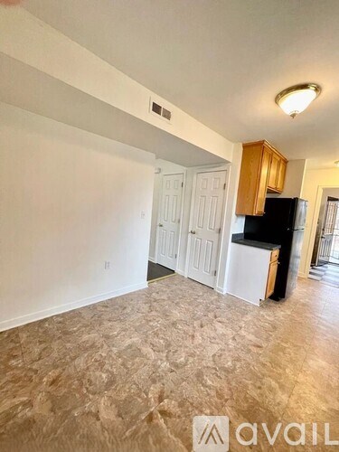 A kitchen area with a black fridge and white cabinets.