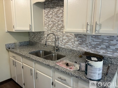 A kitchen with white cabinets and a granite countertop.