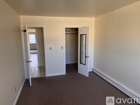 A carpeted room with two doors and one window.