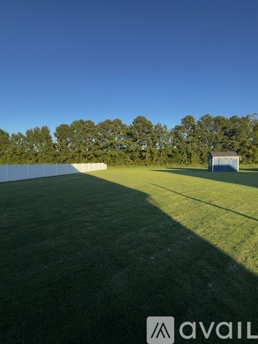 A field with a building and trees in the distance.