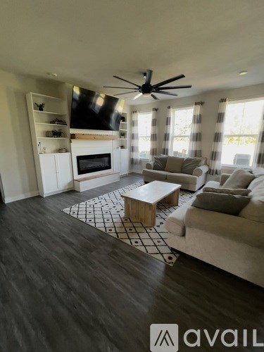 A living room with a fireplace and a ceiling fan.