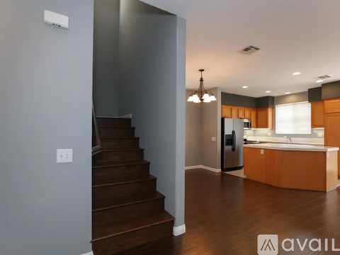A modern kitchen with wooden cabinets and a staircase leading to the upper floor.